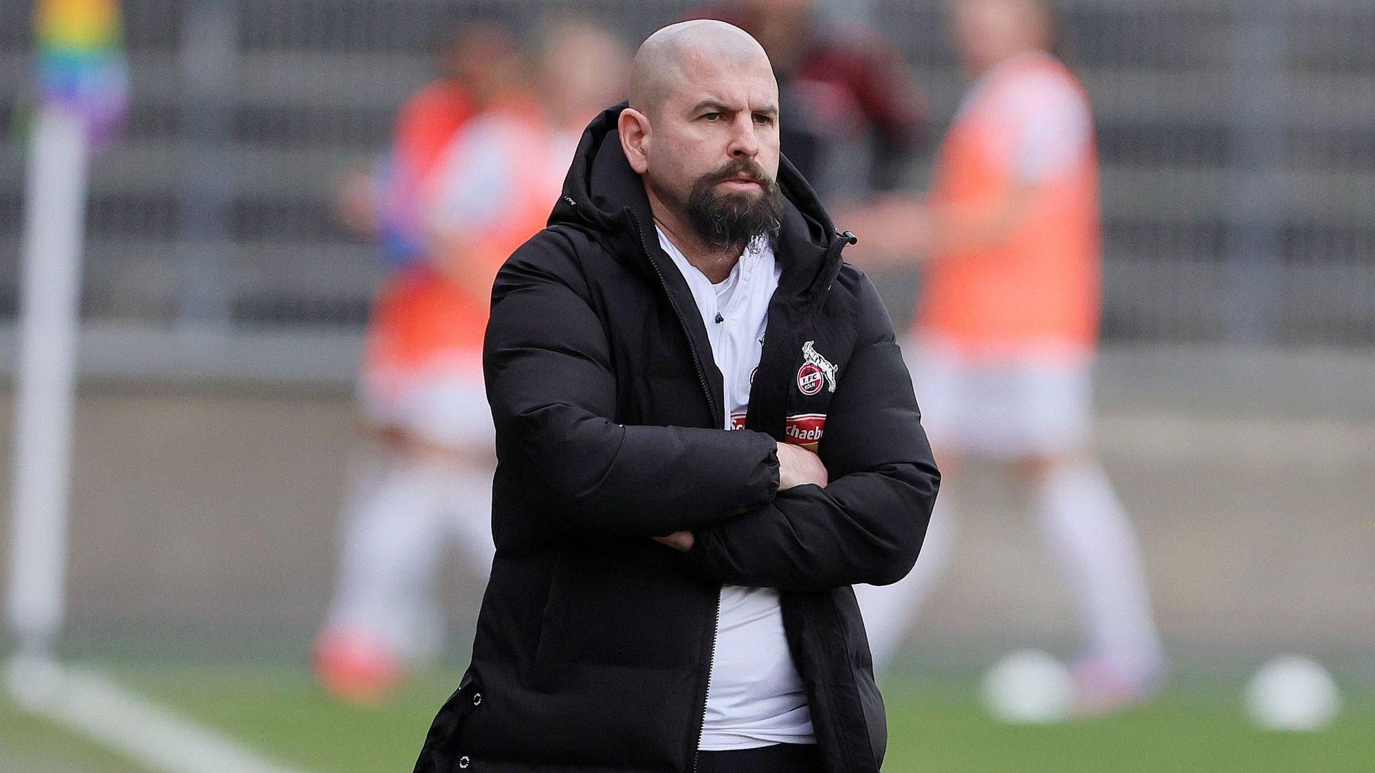 Sascha Glass steht beim Spiel der Frauen des 1. FC Köln gegen den FC Bayern München mit verschränkten Armen an der Seitenlinie.