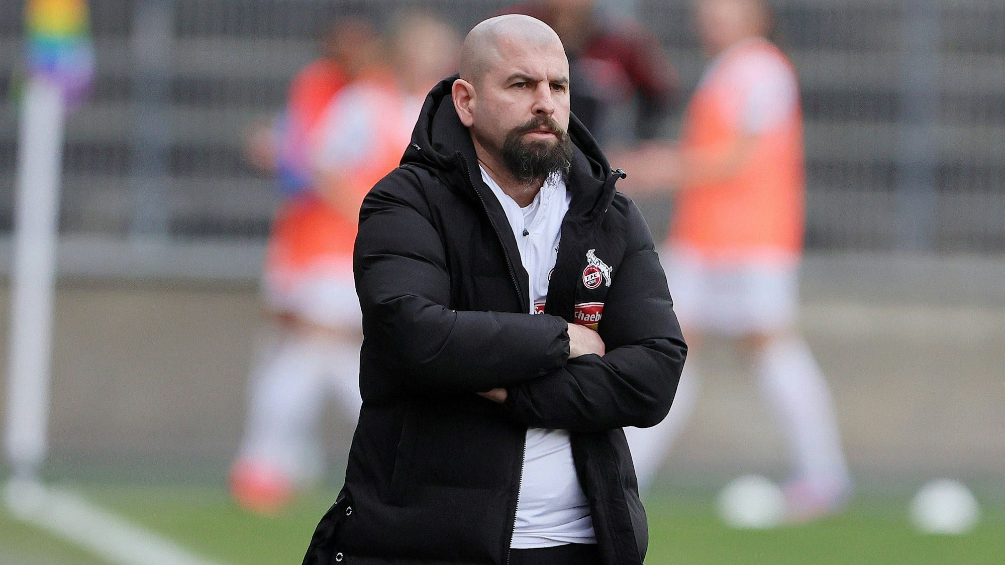 Sascha Glass steht beim Spiel der Frauen des 1. FC Köln gegen den FC Bayern München mit verschränkten Armen an der Seitenlinie.
