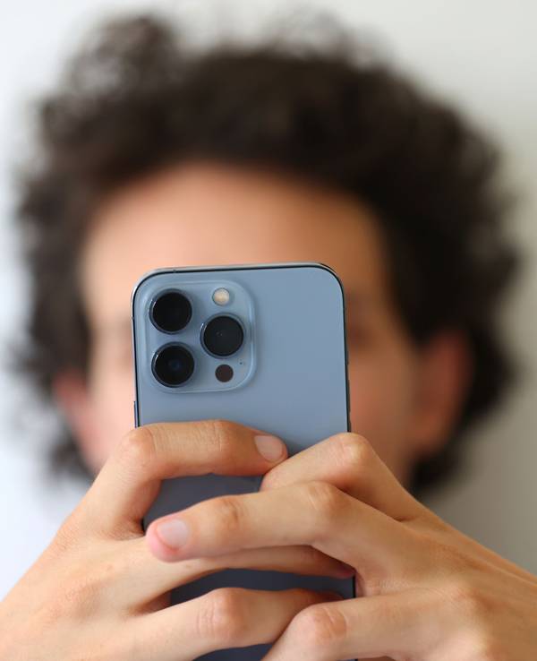 Das Symbolfoto aus dem Jahr 2022 zeigt einen jungen Mann, der mit beiden Händen ein Smartphone festhält.
