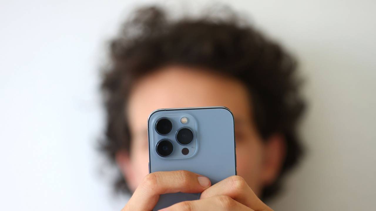 Das Symbolfoto aus dem Jahr 2022 zeigt einen jungen Mann, der mit beiden Händen ein Smartphone festhält.
