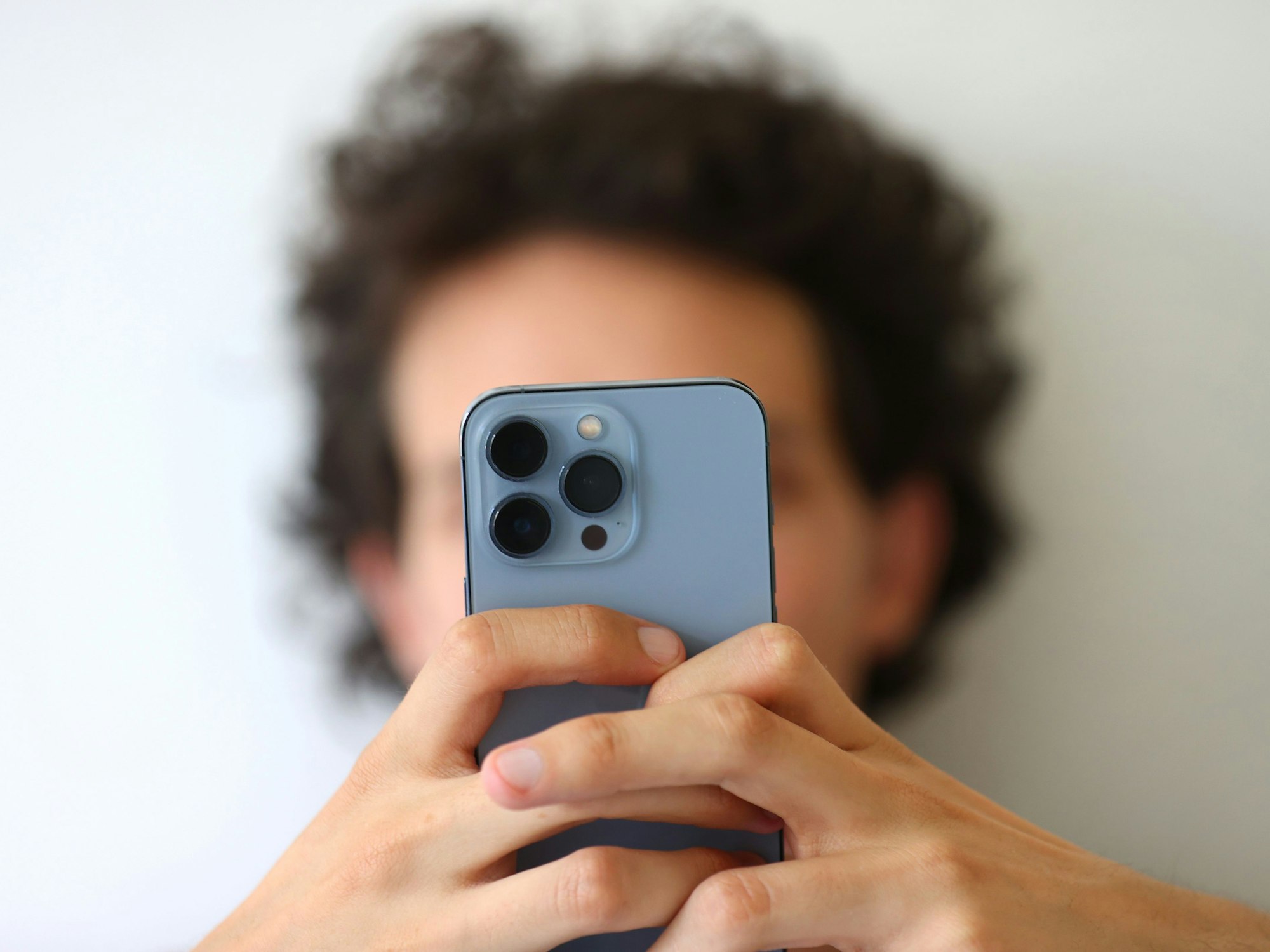 Das Symbolfoto aus dem Jahr 2022 zeigt einen jungen Mann, der mit beiden Händen ein Smartphone festhält.