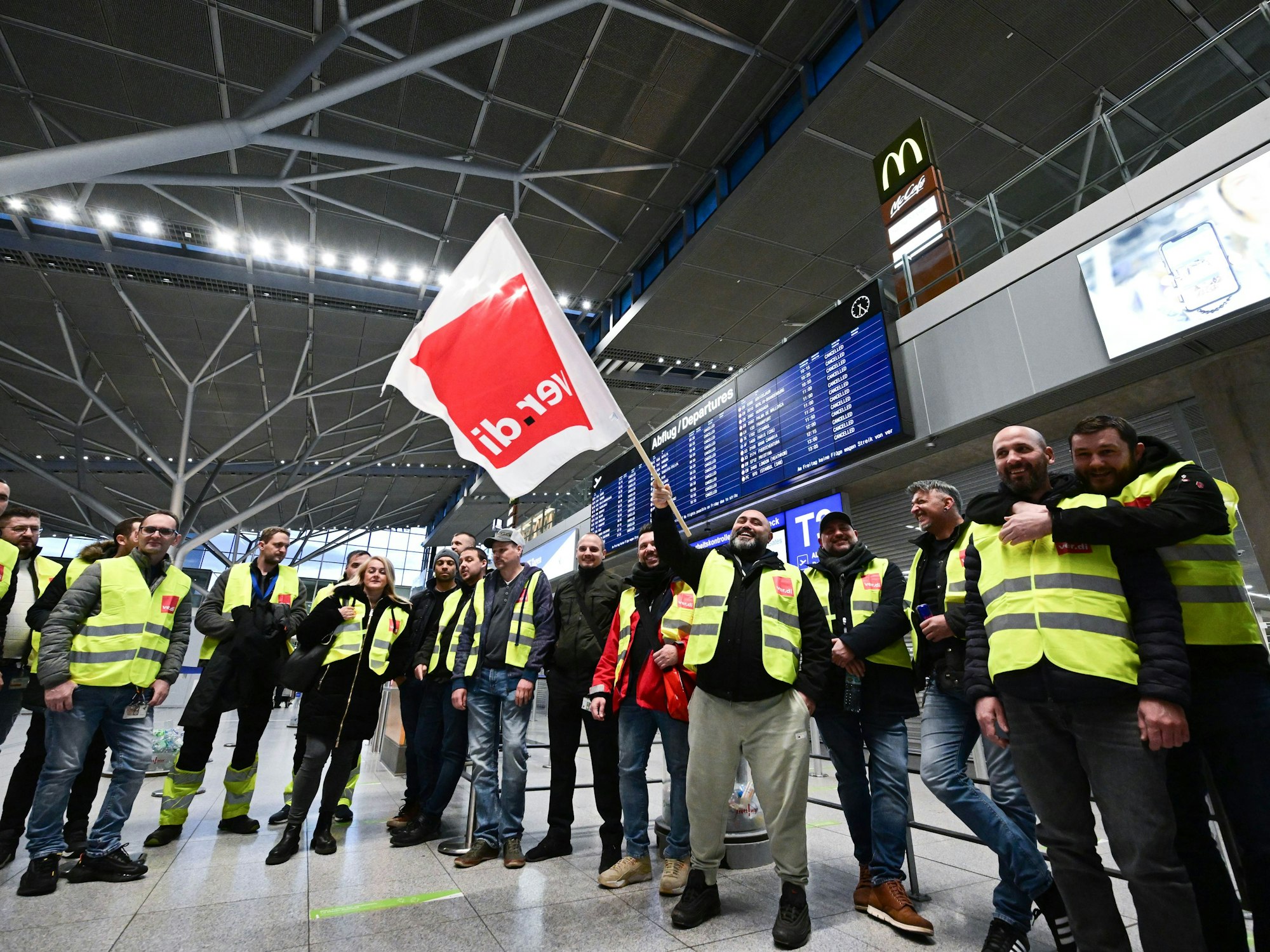 Streikende Mitarbeiterinnen und Mitarbeiter des Flughafens Stuttgart stehen am 17. März 2023 mit Westen der Gewerkschaft Verdi in der leeren Abflughalle im Stuttgarter Flughafen.