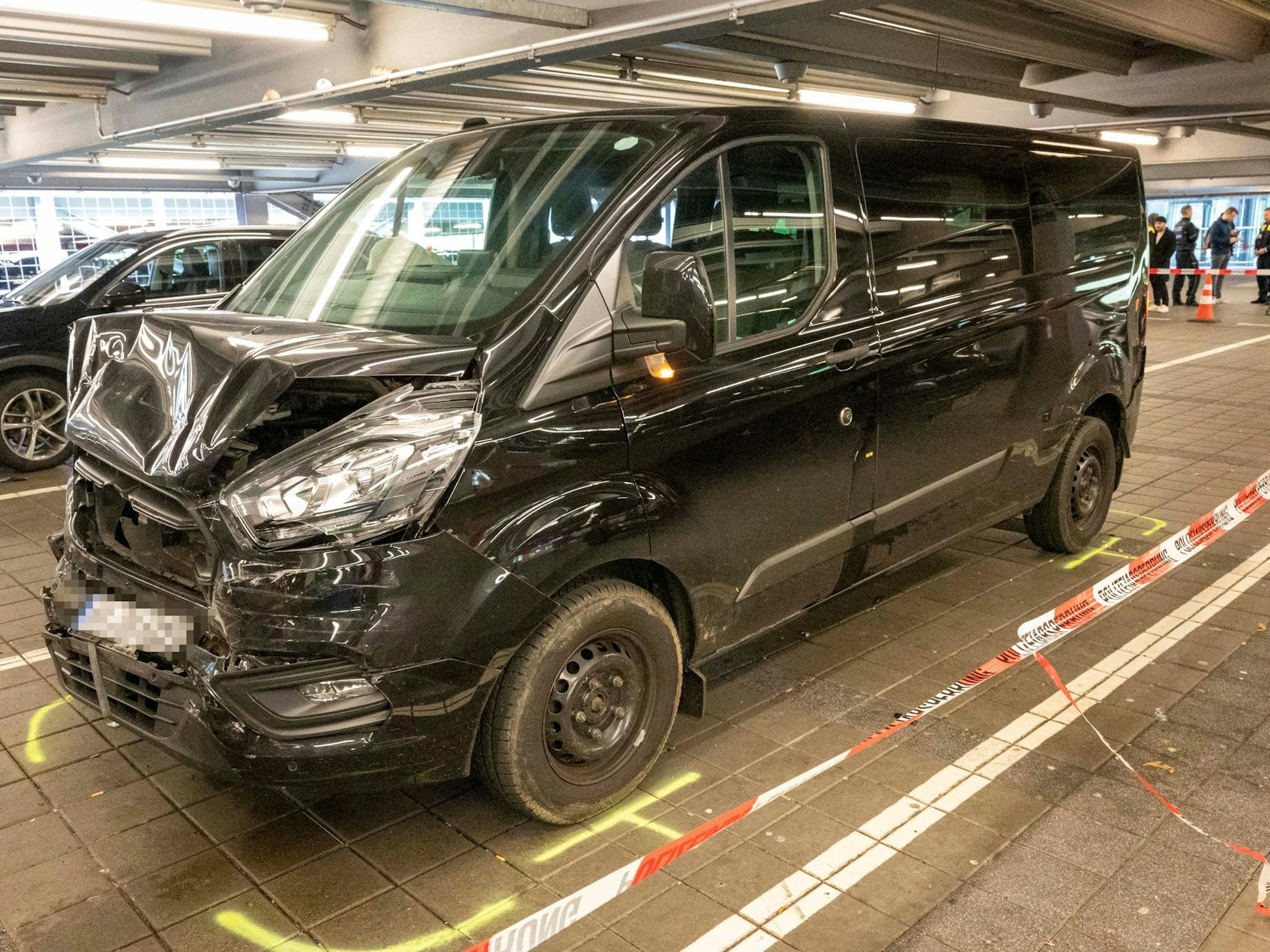 Der beschädigte Minivan steht im Parkhaus, die Polizei hat den Bereich mit Flatterband abgesperrt.
