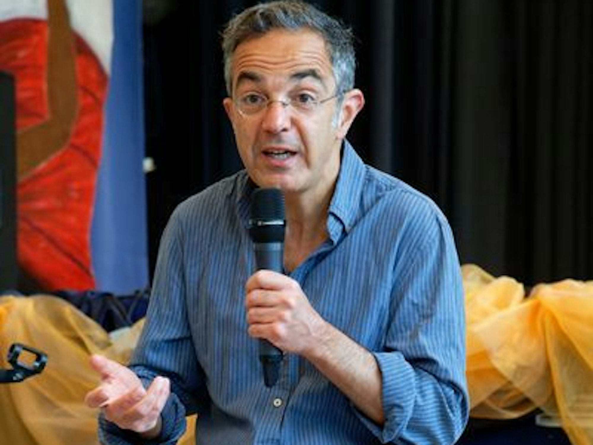 Schriftsteller Navid Kermani sitzt auf einer Bank und spricht in ein Mikrofon.