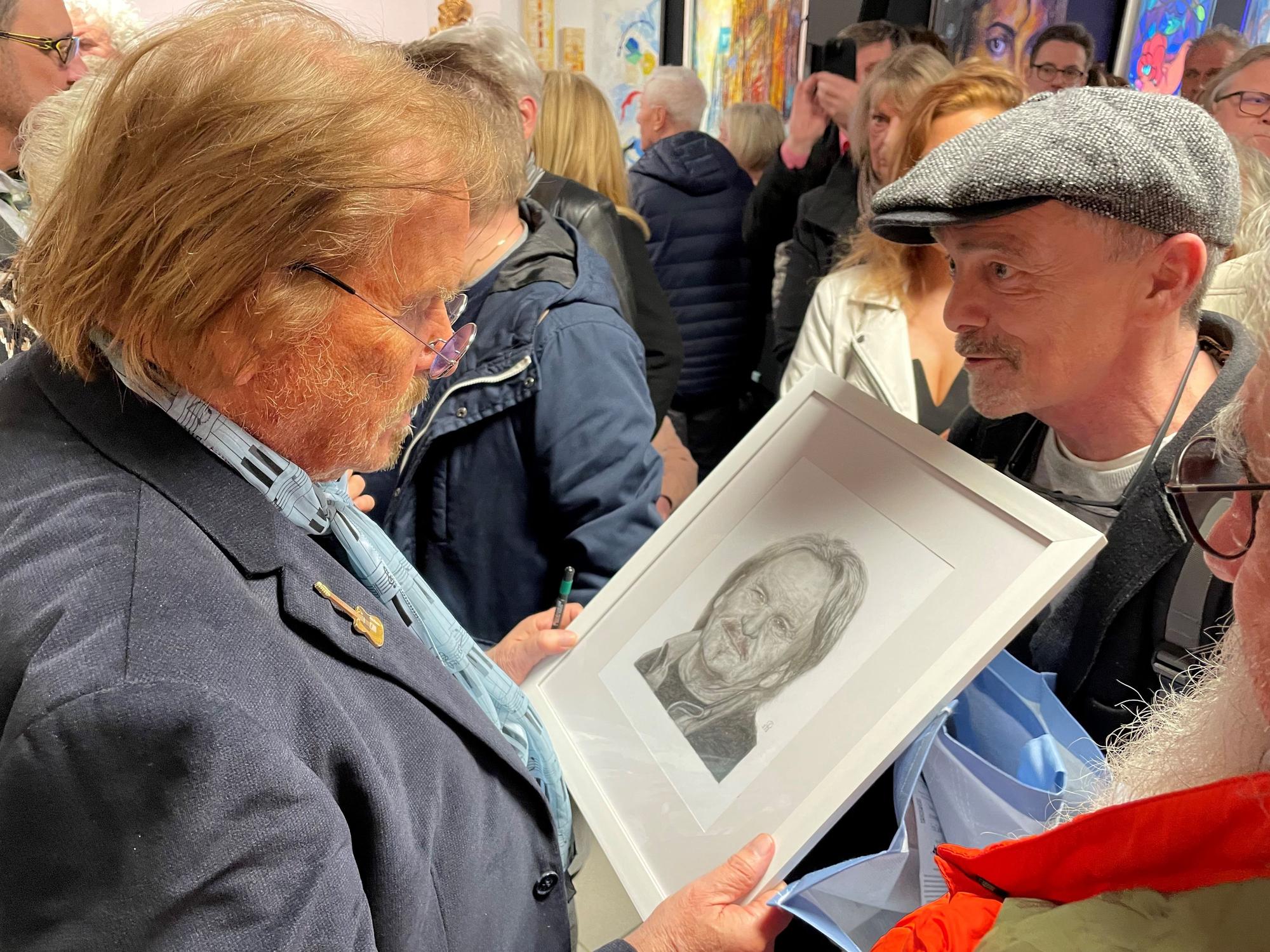 Ein Fan überreicht Frank Zander ein Bild.