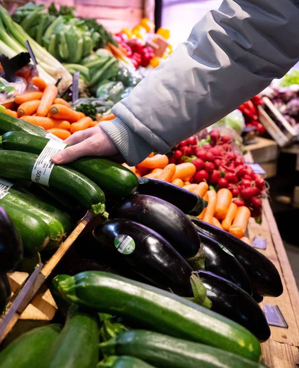 Hier zu sehen, eine Person greift nach einem Doppelpack Zucchini in der Gemüseabteilung eines Supermarktes.