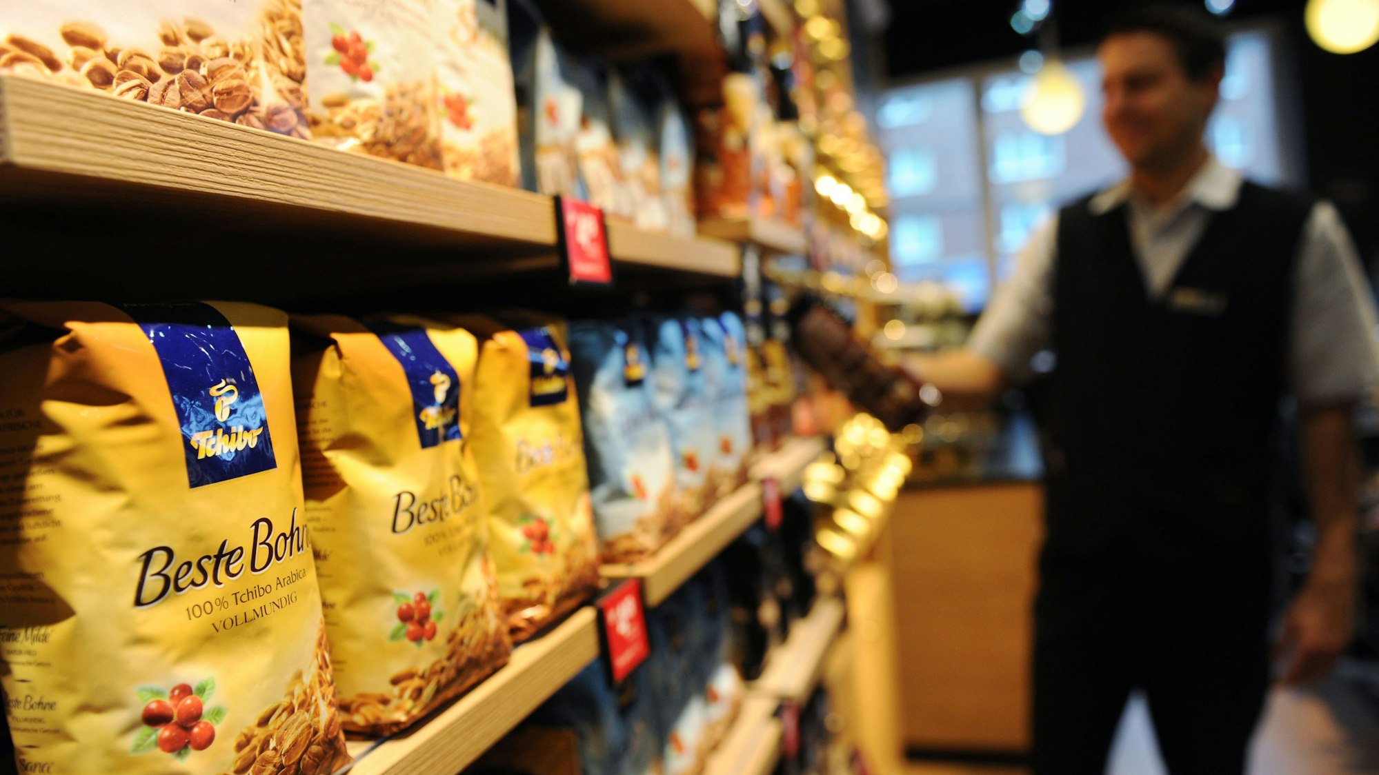 Ein Mitarbeiter nimmt eine Kaffeepackung aus einem Regal.
