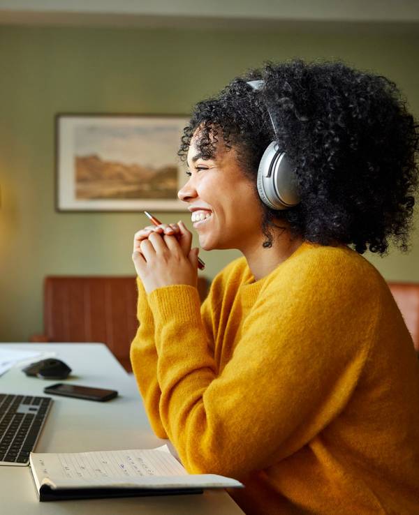 Businesswoman with headphones smiling during video conference. Multiracial male and female professionals are attending online meeting. They are discussing business strategy.