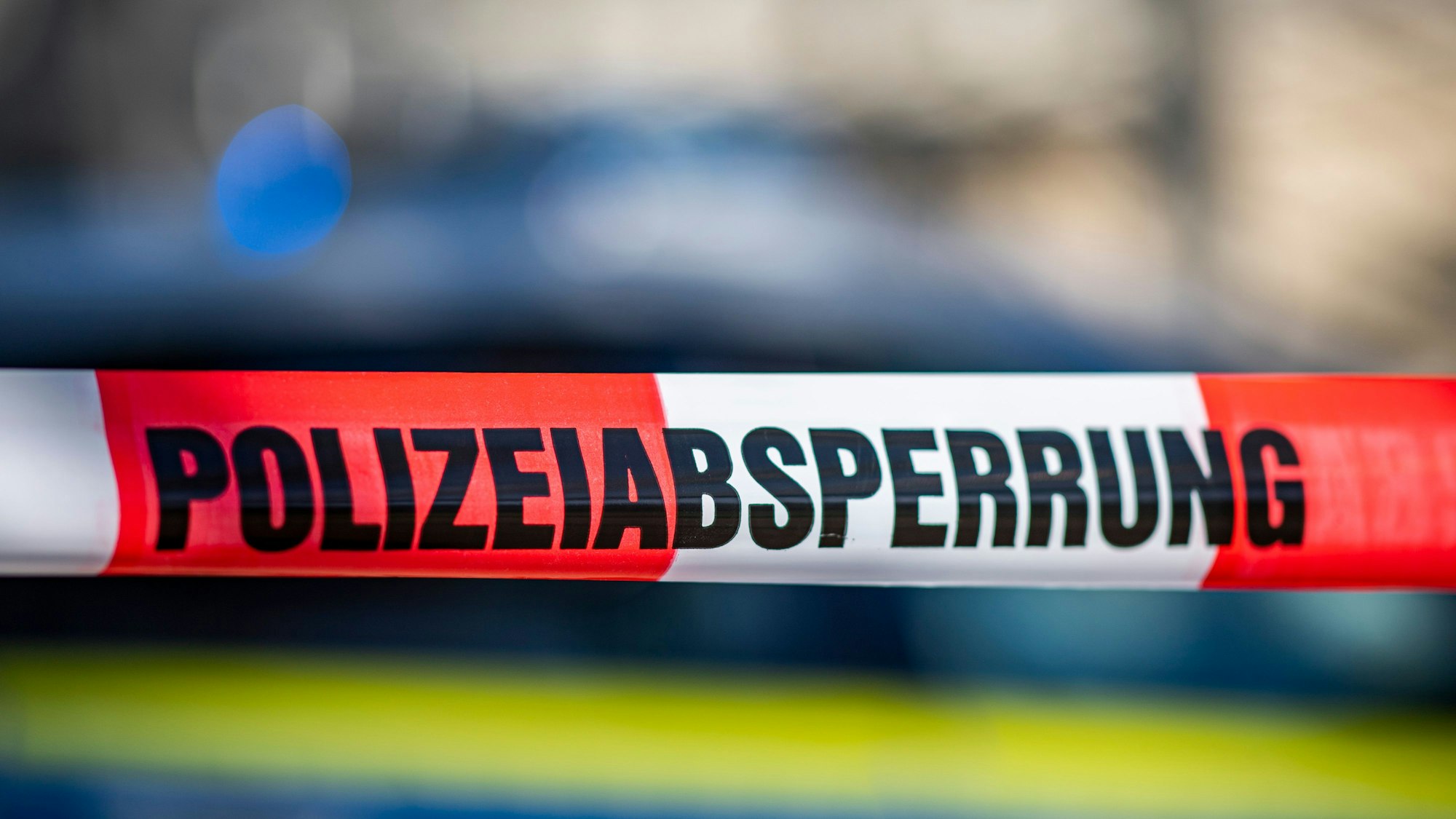 Ein Absperrband mit der Aufschrift «Polizeiabsperrung» ist vor einem Polizeiwagen aufgespannt.