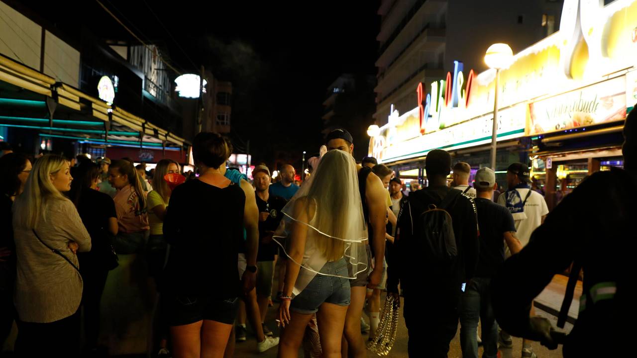 In der Bierstraße am Ballermann gehen Menschen an den Bars Bierkonig und Bamboleo vorbei.