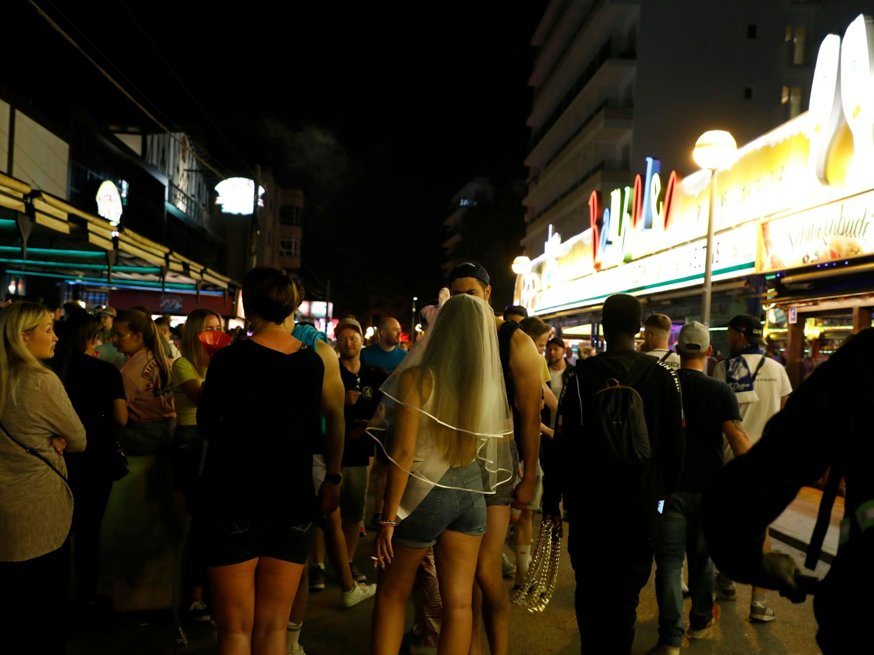 In der Bierstraße am Ballermann gehen Menschen an den Bars Bierkonig und Bamboleo vorbei.
