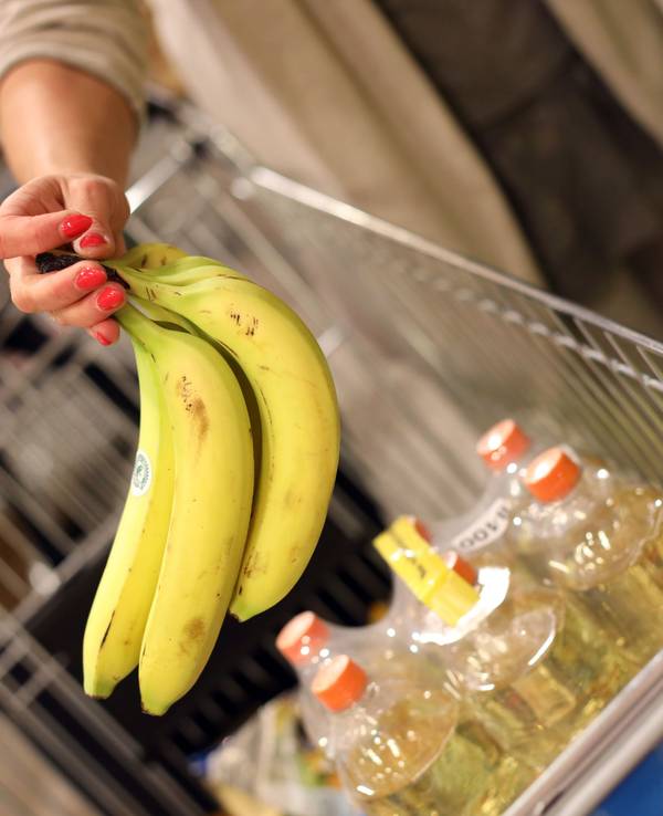 Eine Kundin legt Bananen in ihren Einkaufskorb.