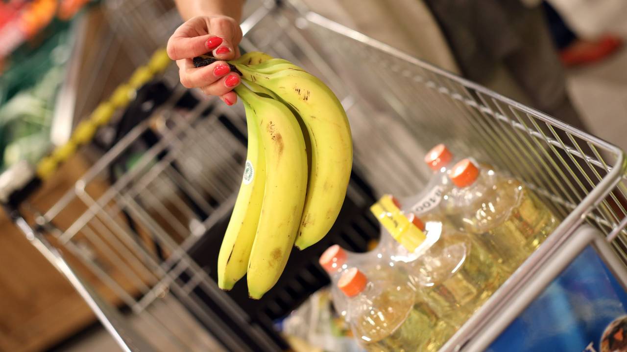 Eine Kundin legt Bananen in ihren Einkaufskorb.