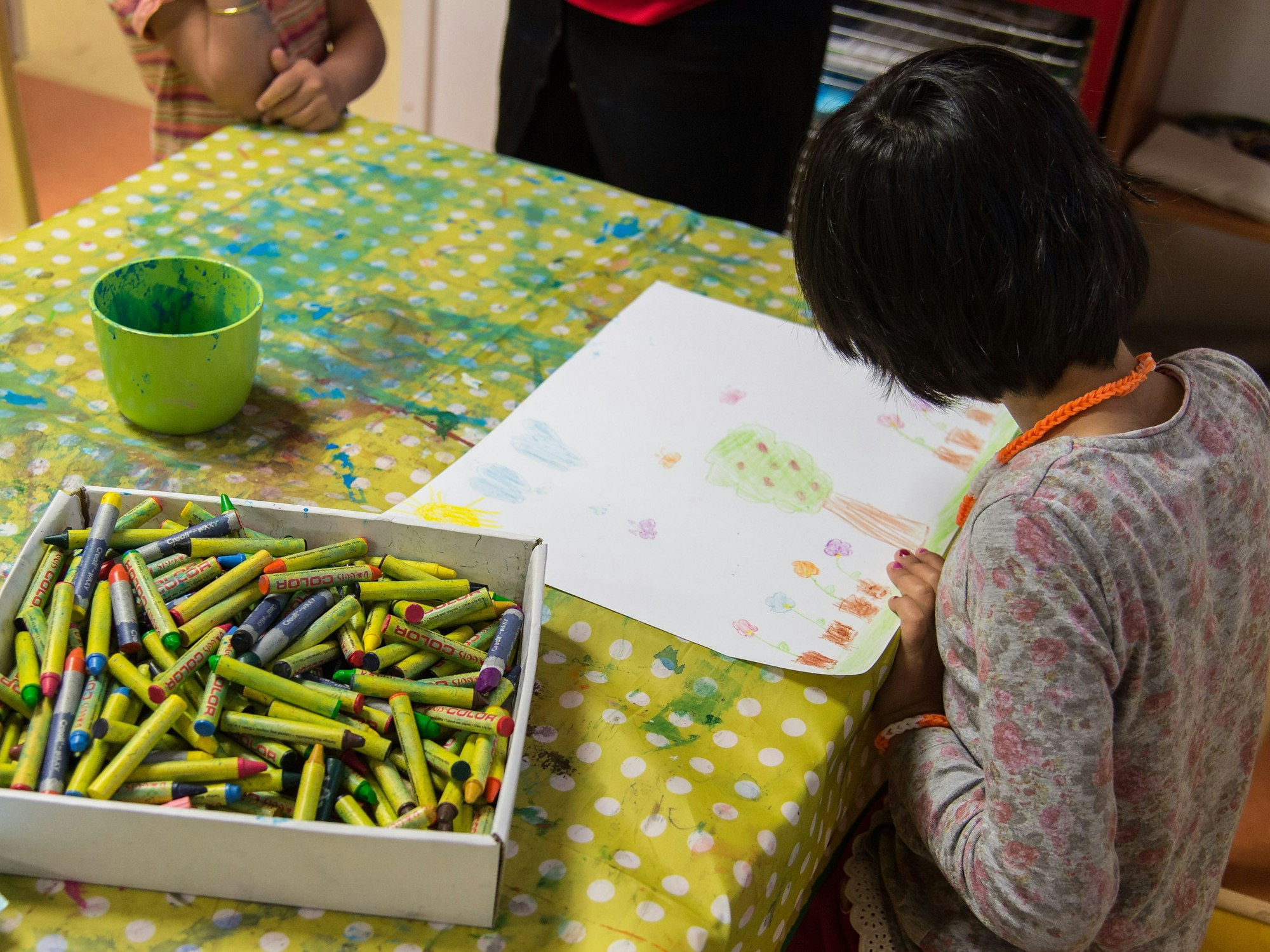 Unser Symbolbild zeigt ein Kind in einer Kita in Baden-Württemberg, das ein Bild mit Wachsmalstiften malt.