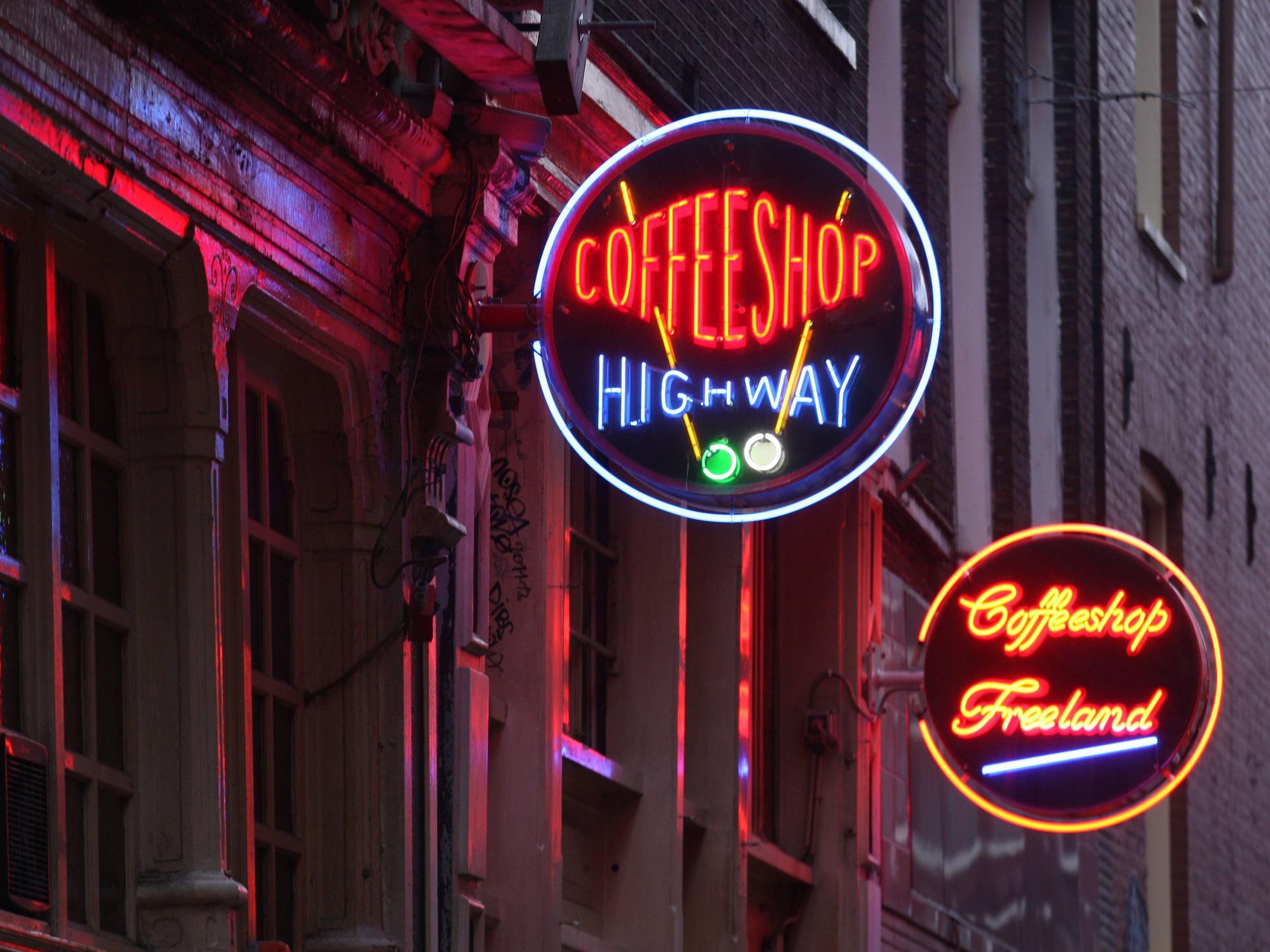 Das Foto zeigt zwei beleuchtete Neon-Schilder von Coffeeshops im Rotlichtviertel Amsterdams.