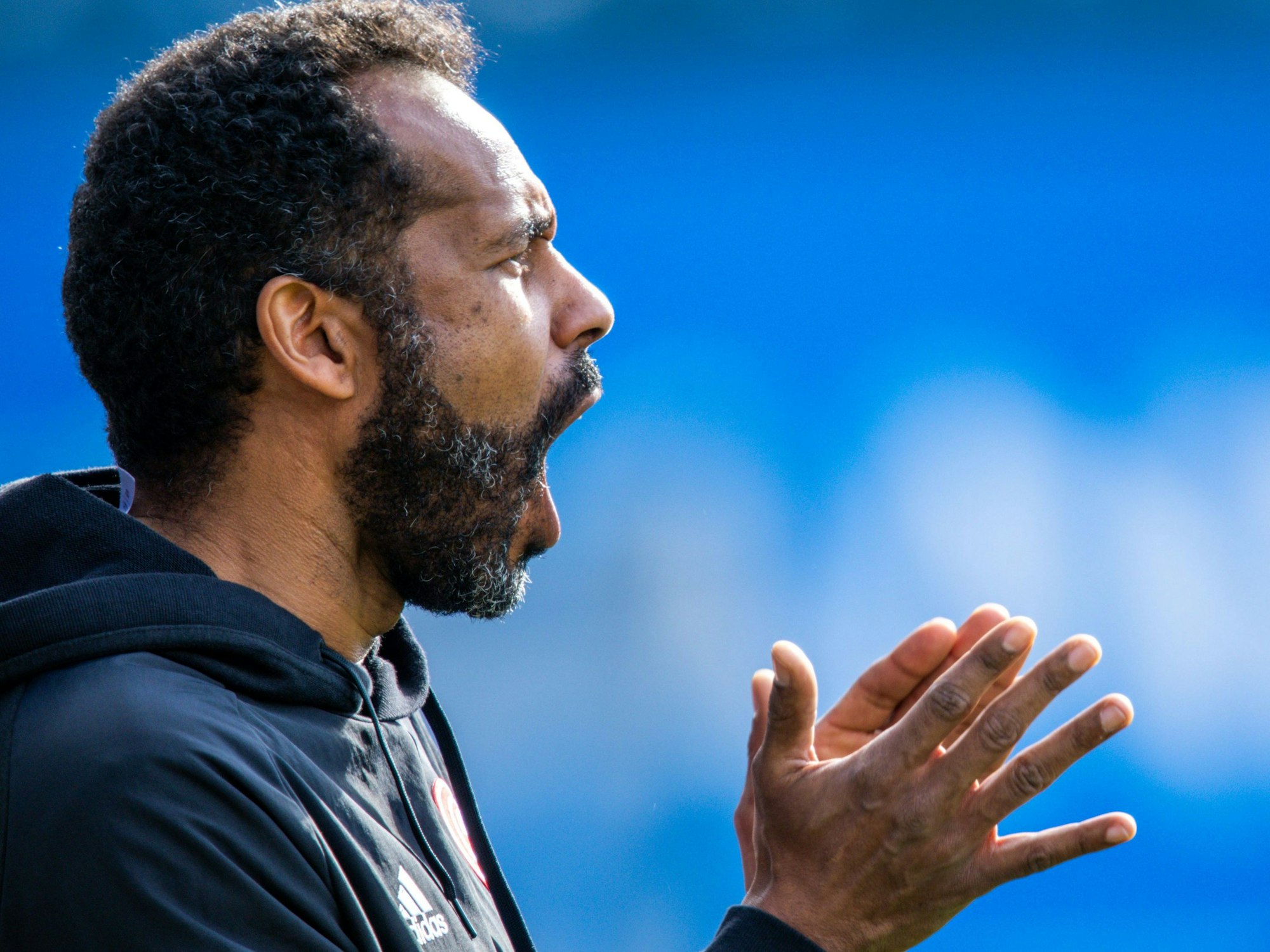 Daniel Thioune klatscht am Spielfeldrand in die Hände und ruft Anweisungen.