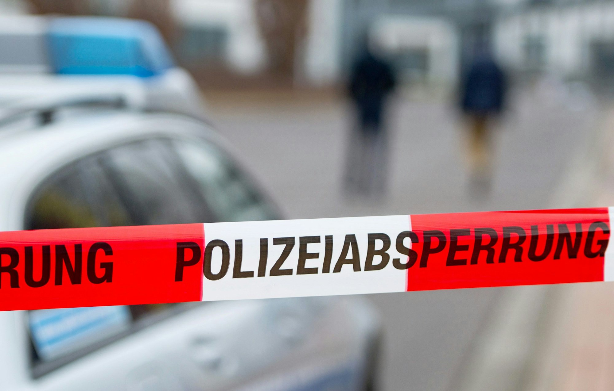 Ein Polizeiabsperrband ist vor einem Polizeiwagen zu sehen.