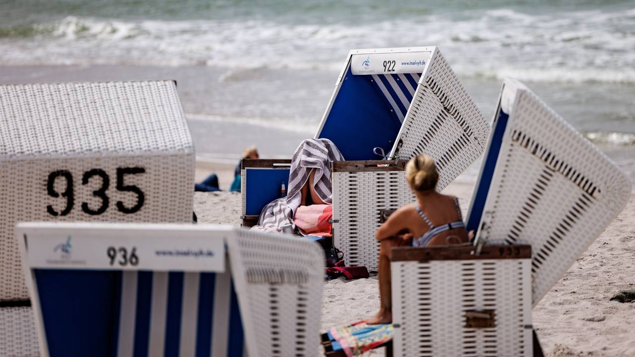 Das Foto aus dem Jahr 2022 zeigt mehrere weiß-blaue Strandkörbe am Sylter Strand. Im Hintergrund schlagen Wellen der Nordsee ans Ufer.