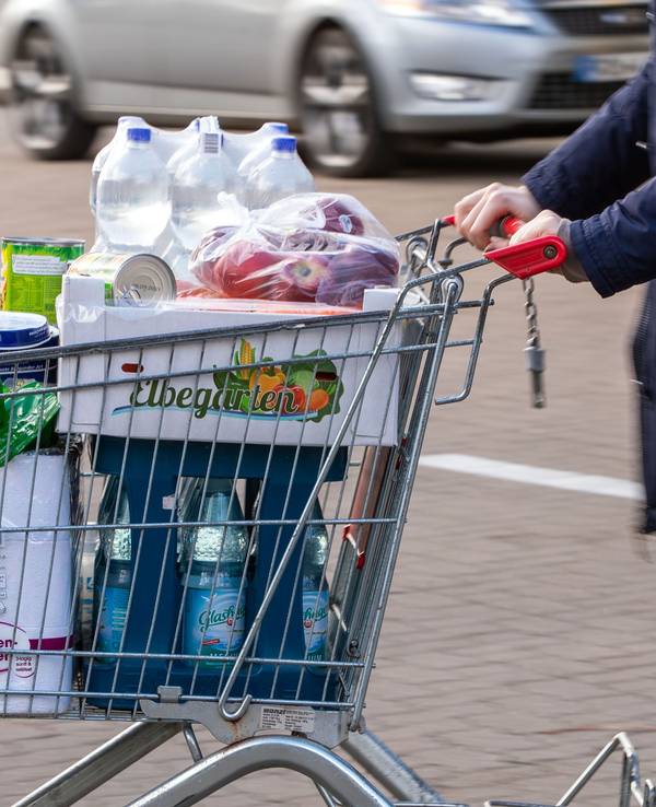 Auf dem Bild sehen sie einen mit Lebensmitteln gefüllten Einkaufswagen auf einem Supermarktparkplatz.