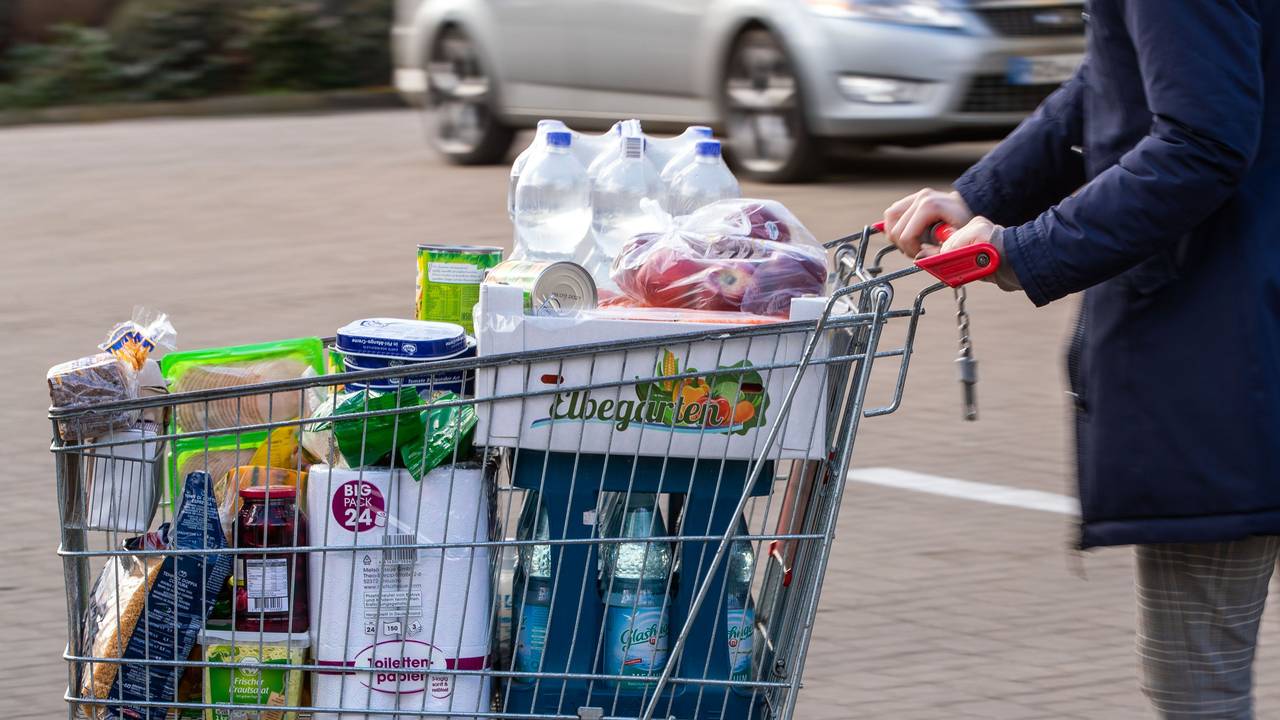 Auf dem Bild sehen sie einen mit Lebensmitteln gefüllten Einkaufswagen auf einem Supermarktparkplatz.