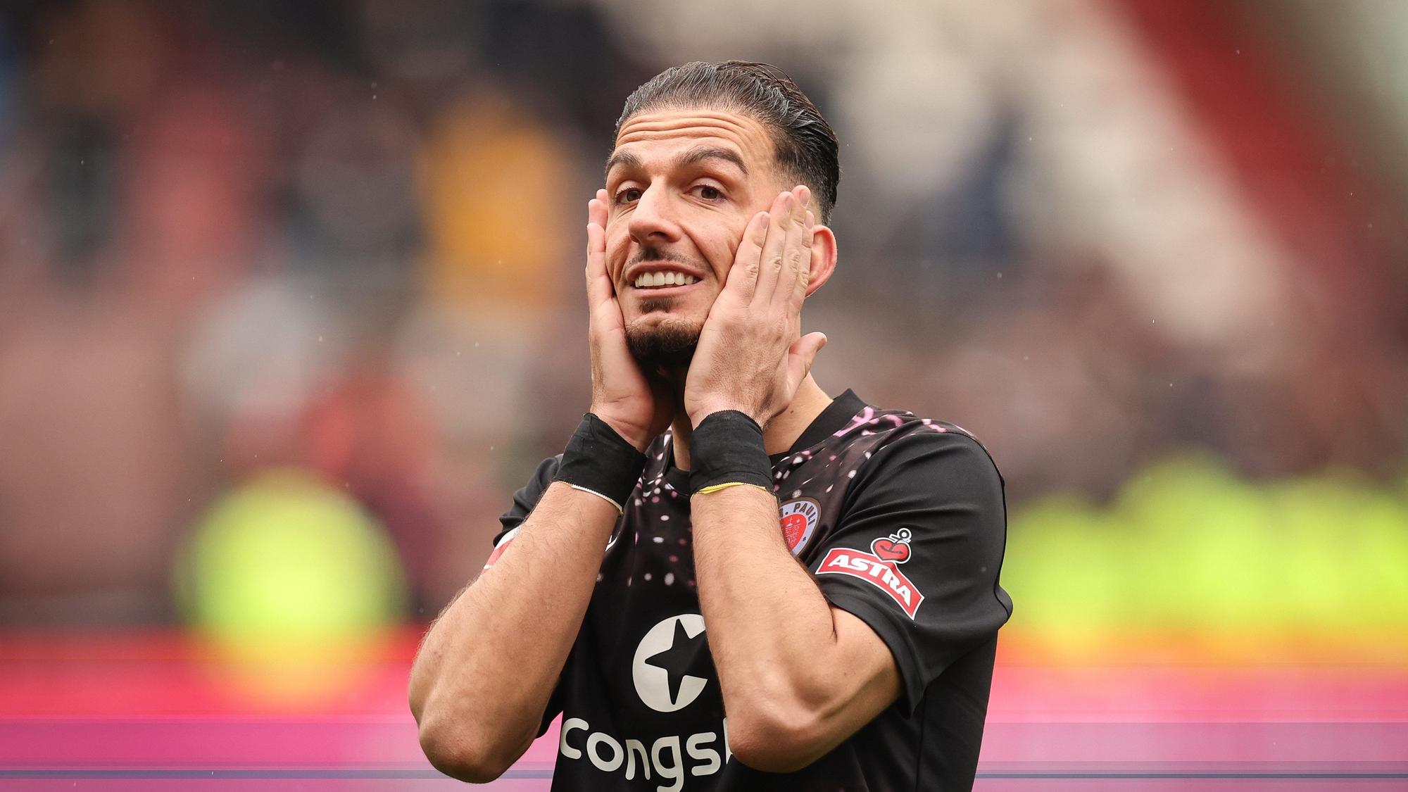Sankt Paulis Leart Paqarada steht nach dem Spiel auf dem Platz und fasst sich mit den Händen ans Gesicht.