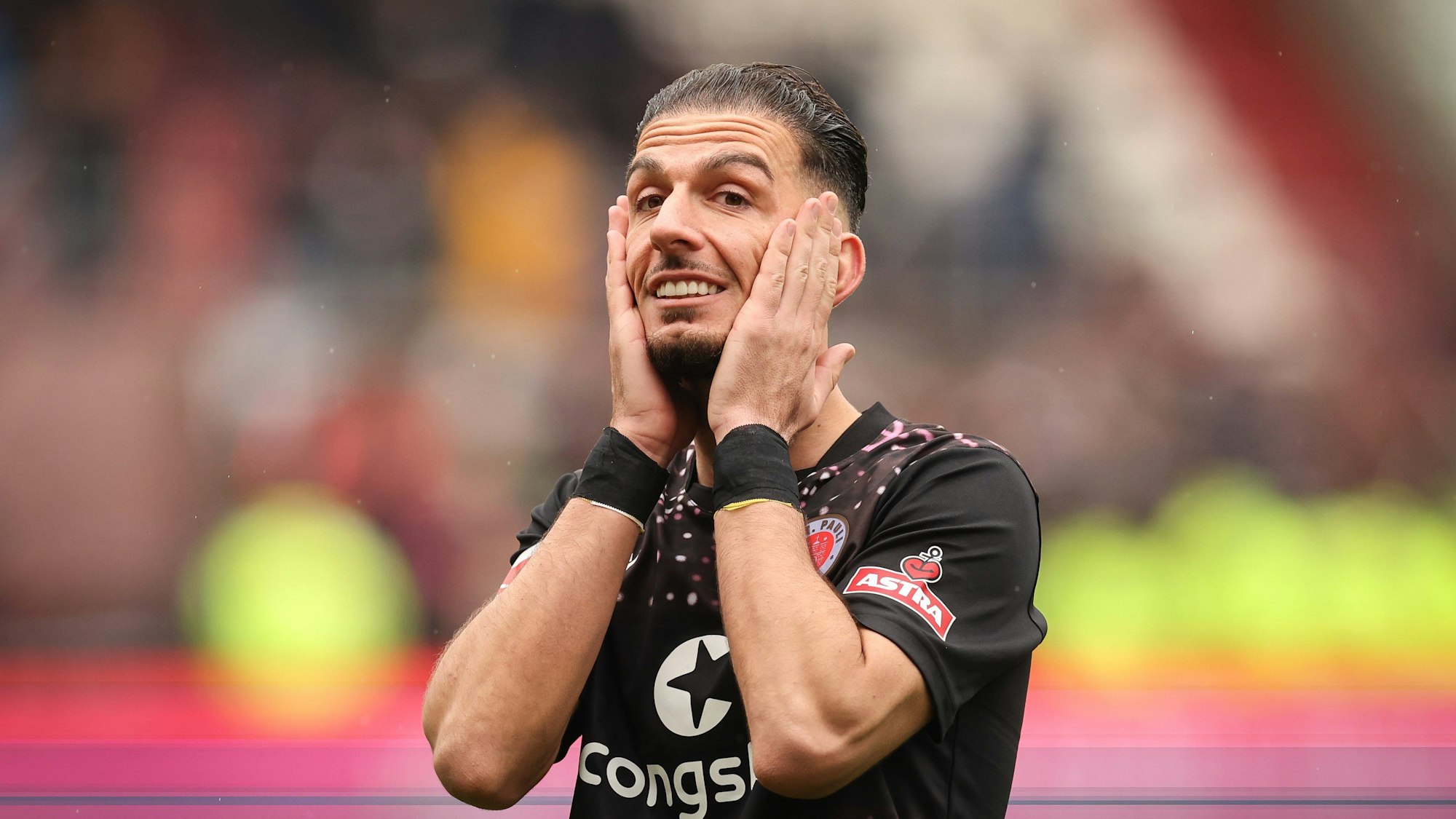 Sankt Paulis Leart Paqarada steht nach dem Spiel auf dem Platz und fasst sich mit den Händen ans Gesicht.