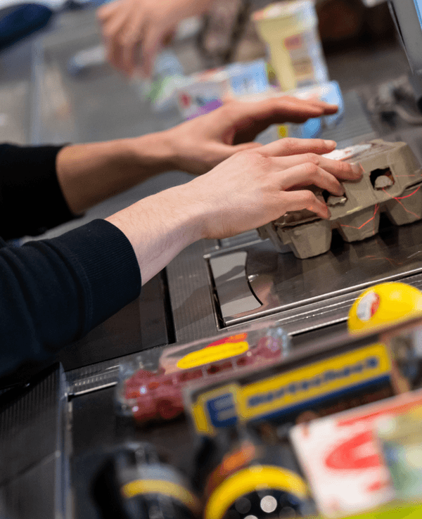 Ein Kassierer scannt in einem Supermarkt an der Kasse die Produkte.