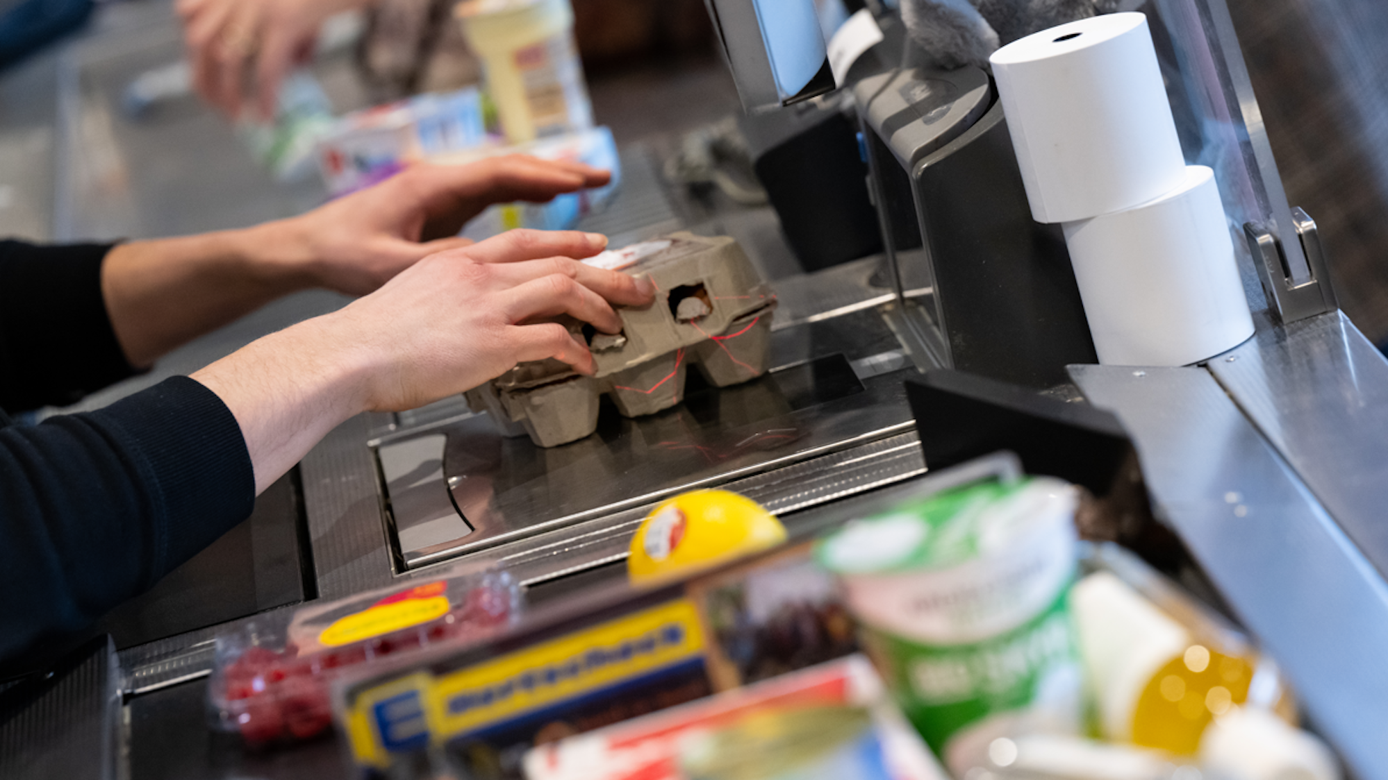 Ein Kassierer scannt in einem Supermarkt an der Kasse die Produkte.
