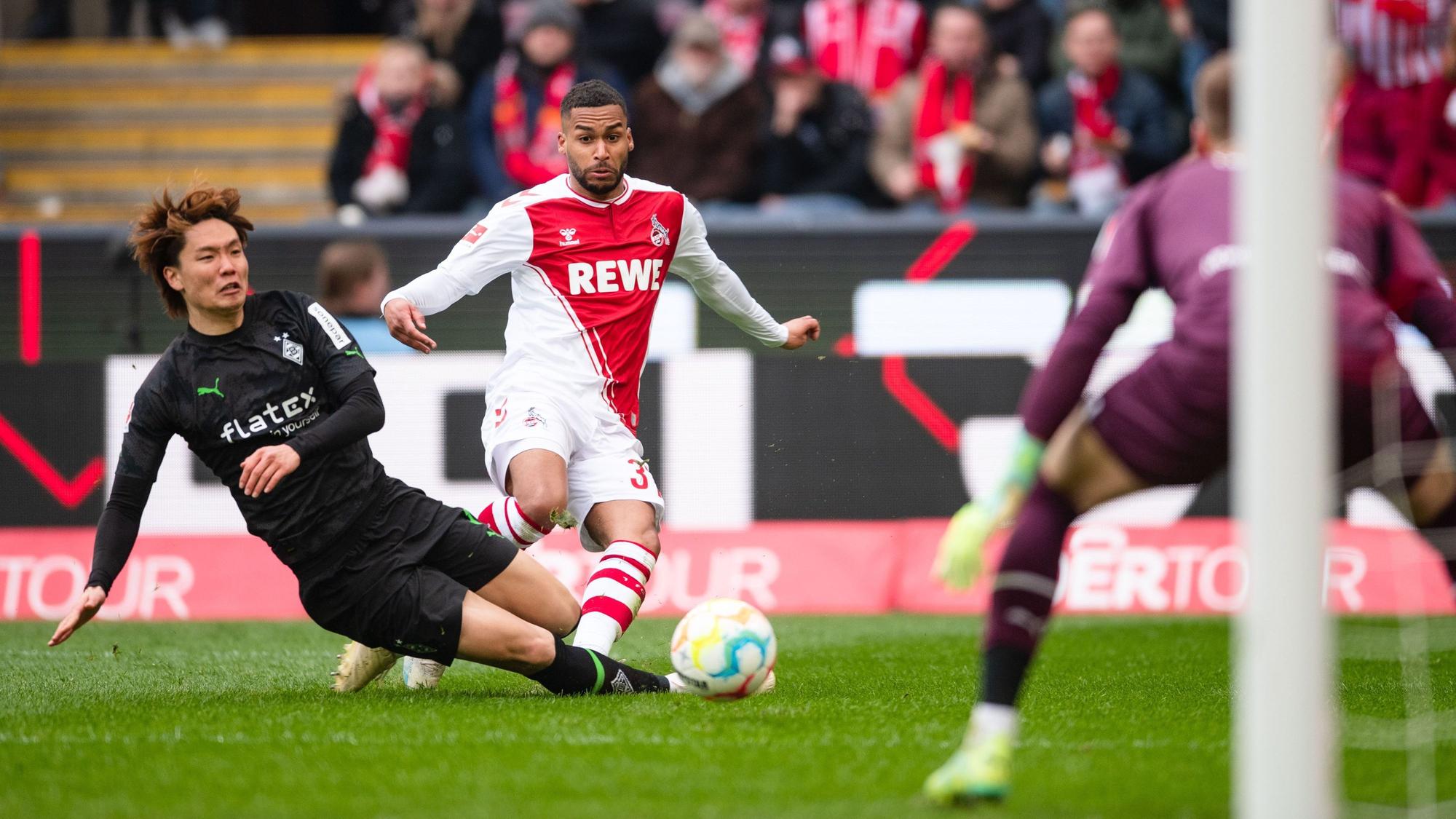 Kölns Linton Maina (M) schießt auf das Tor von Gladbachs Torhüter Jonas Omlin. Gladbachs Ko Itakura (l) versucht ihn aufzuhalten.