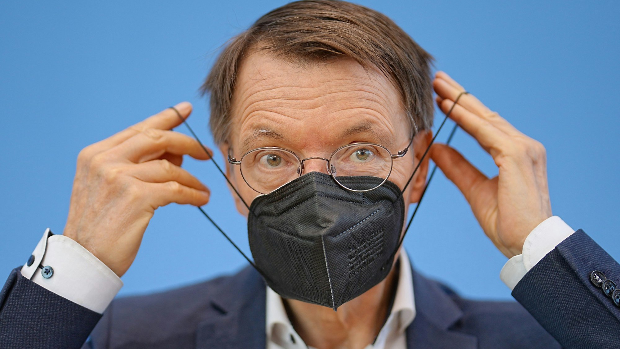 Bundesgesundheitsminister Karl Lauterbach (SPD) zieht eine FFP2-Maske am Ende einer Pressekonferenz zur Corona-Lage im Sommer 2022 in der Bundespressekonferenz auf. Die Maskenpflicht ist bald Geschichte.