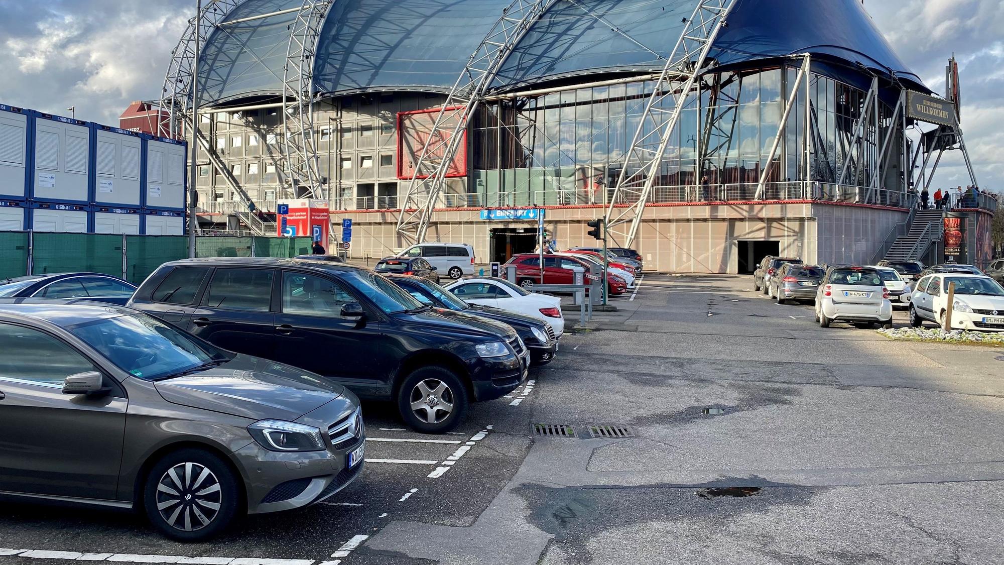 Autos stehen in Parkbuchten. Im Hintergrund ist der Kölner Musical Dome zu sehen.