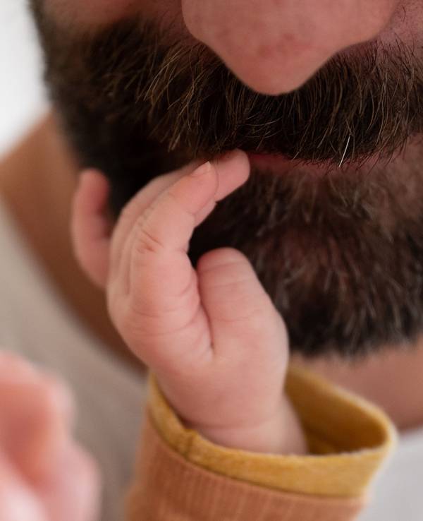 Ein Baby fasst seinem Vater in den Bart.