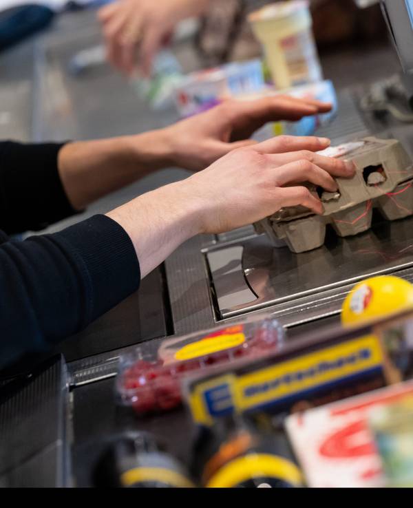 Ein Kassierer scannt in einem Supermarkt an der Kasse die Produkte.