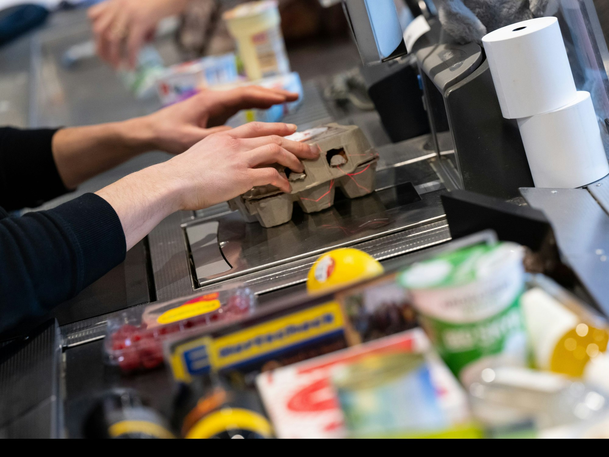 Ein Kassierer scannt in einem Supermarkt an der Kasse die Produkte.