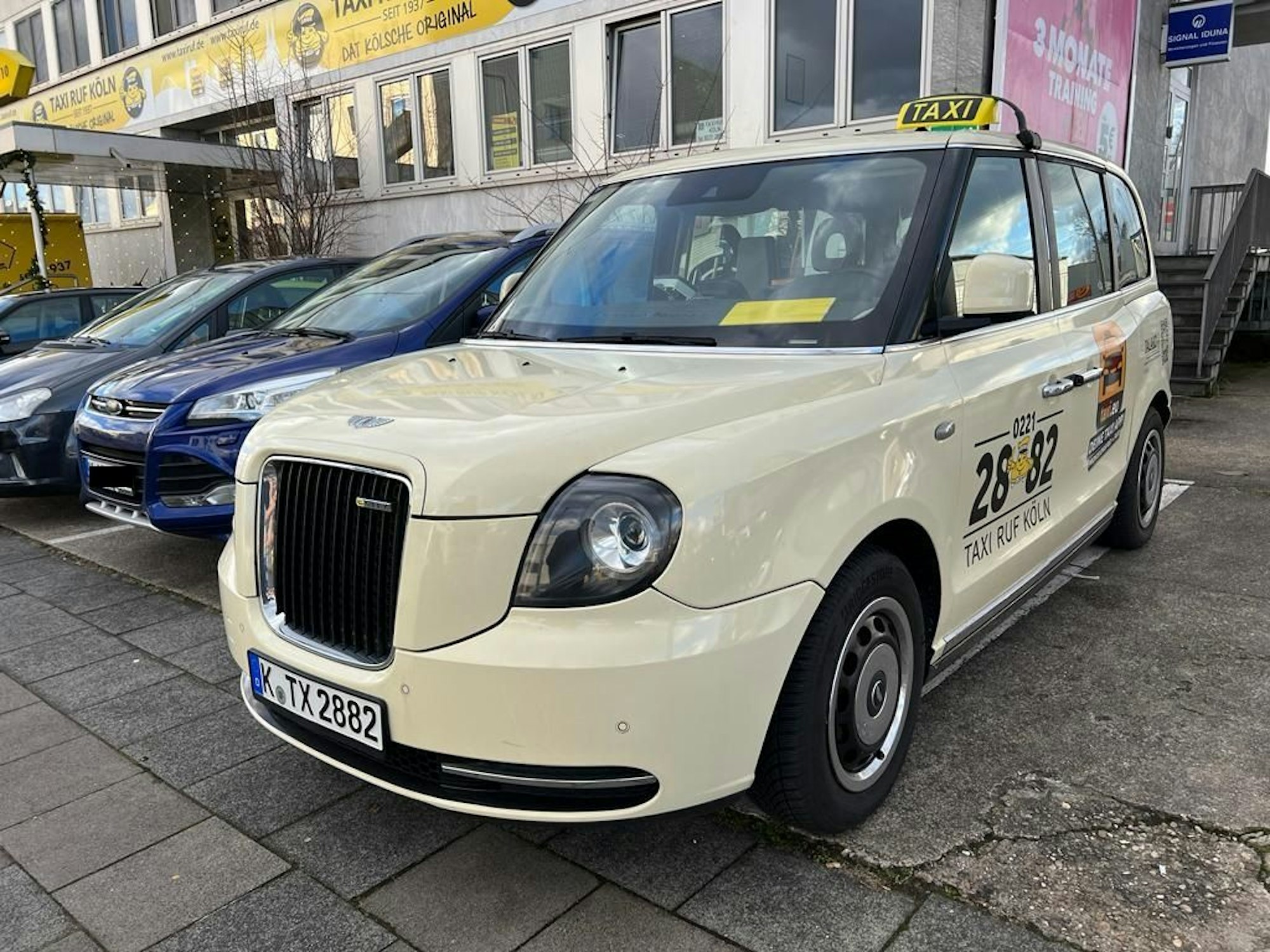 Ein Taxi steht auf einem Parkplatz neben anderen Autos.