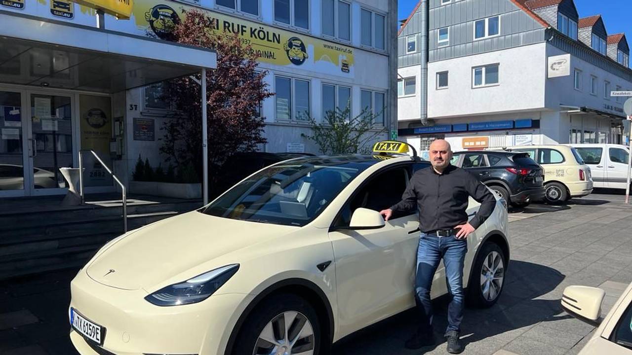 Ein Taxi-Fahrer steht neben seinem Auto.