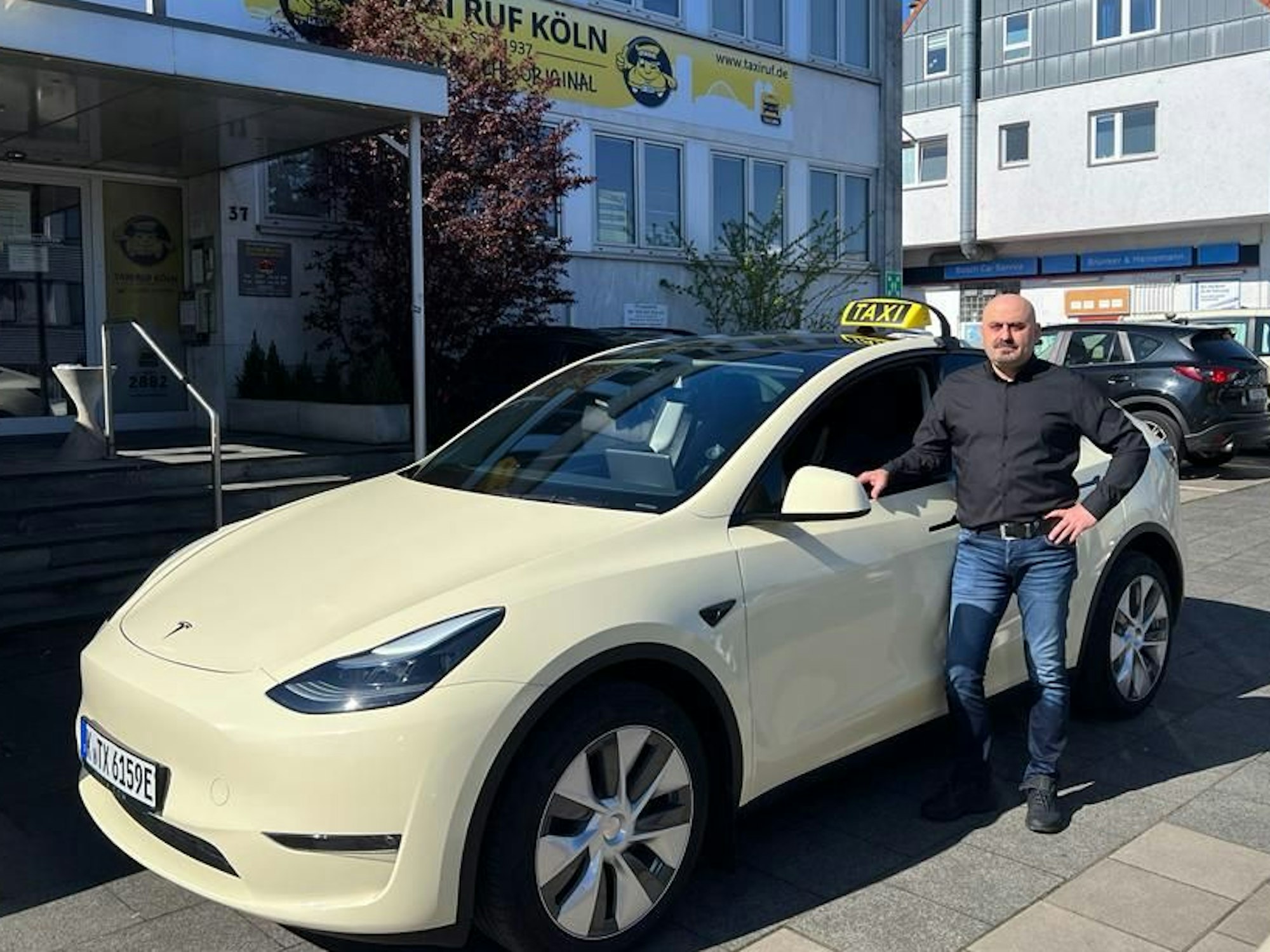 Ein Taxi-Fahrer steht neben seinem Auto.