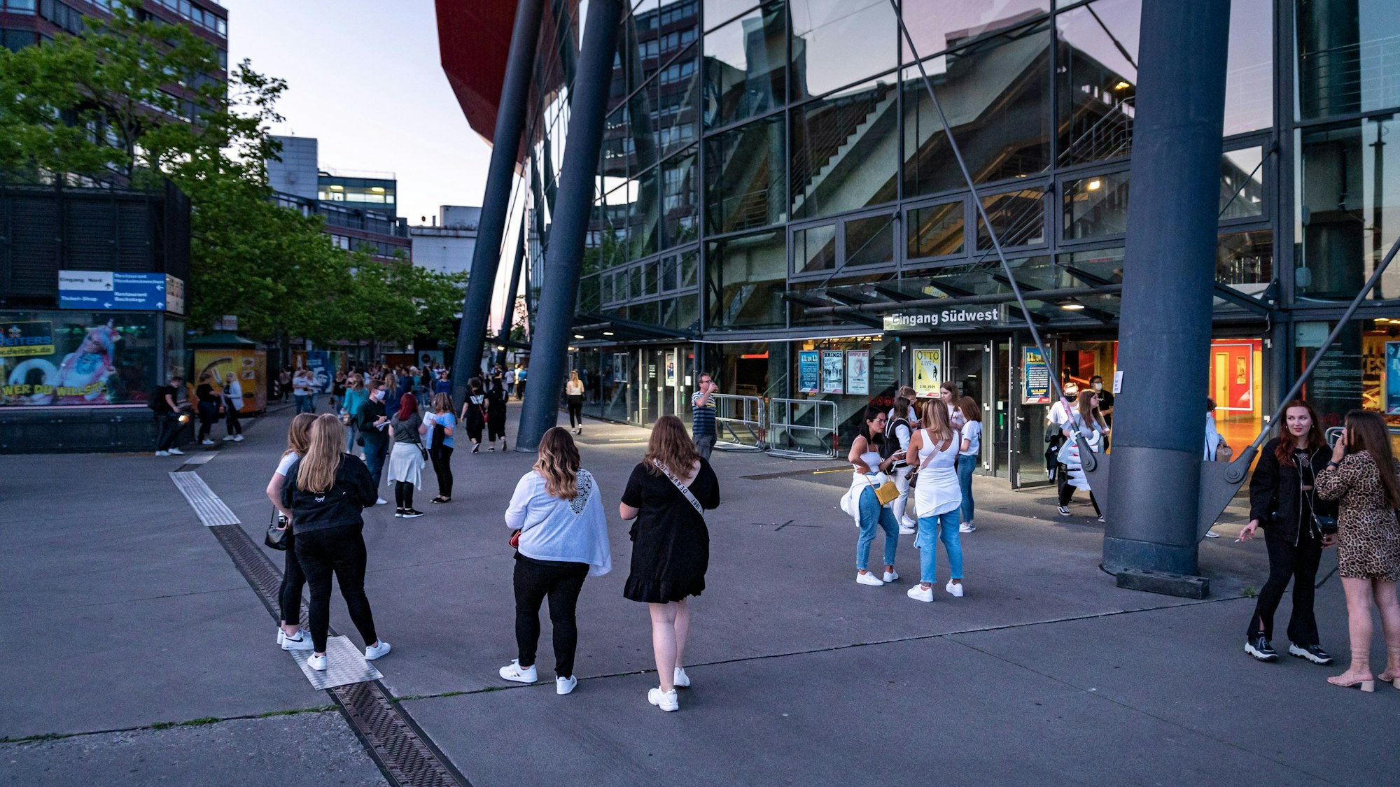 Fans stehen vor der Lanxess-Arena in Köln und warten auf Einlass.