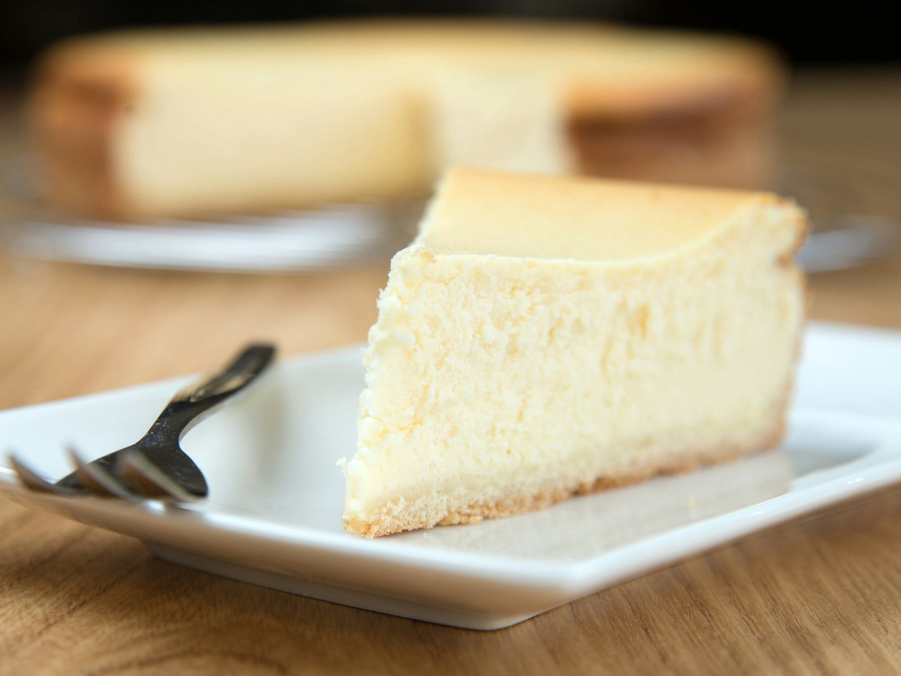 Auf dem Foto sehen Sie ein Stück Käsekuchen auf einem Teller, daneben eine silberne Gabel.