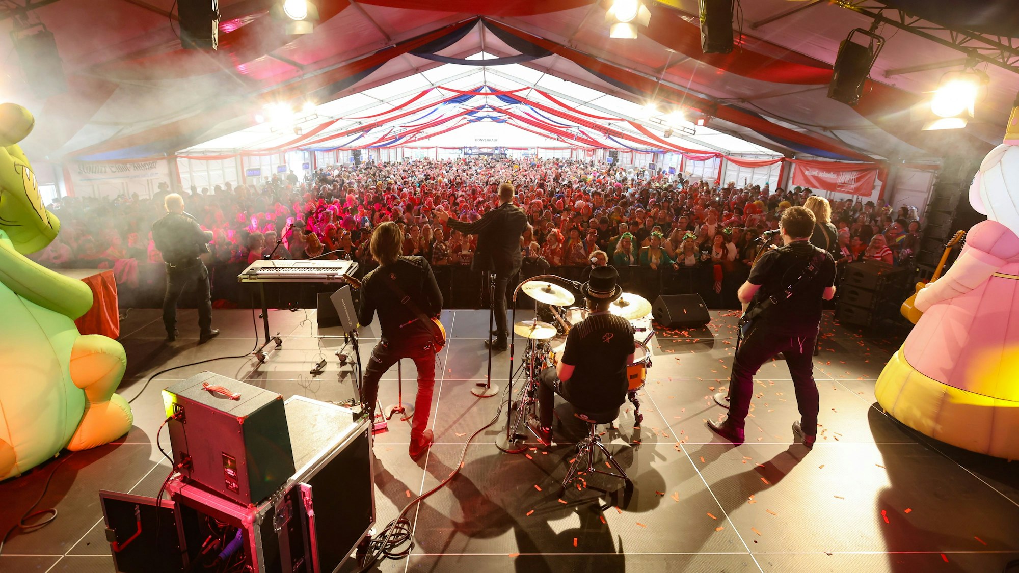 Blick von hinten auf die Bühne beim EXPRESS-Zelt in Köln. Die Höhner performen vor den vielen Menschen.