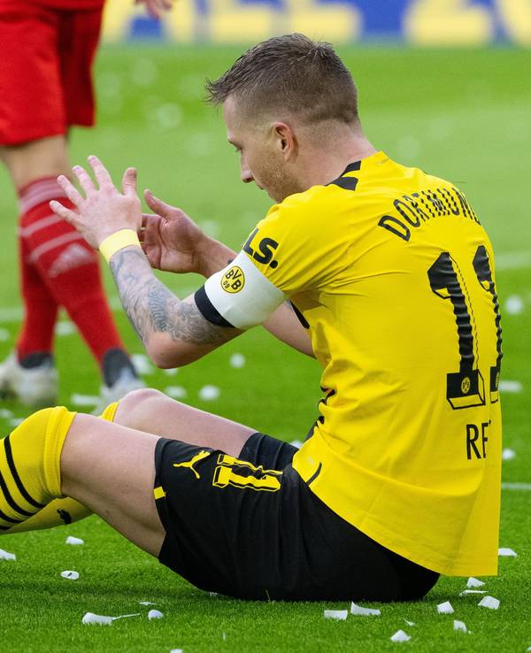 Marco Reus von Dortmund sitzt auf dem Rasen.