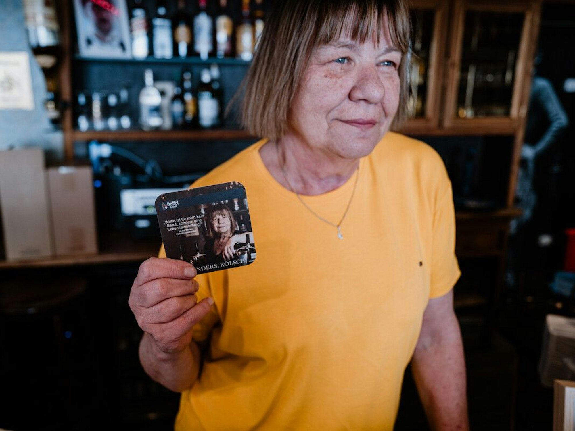 Kult-Wirtin Uschi hält ihren eigenen Bierdeckel in die Kamera.