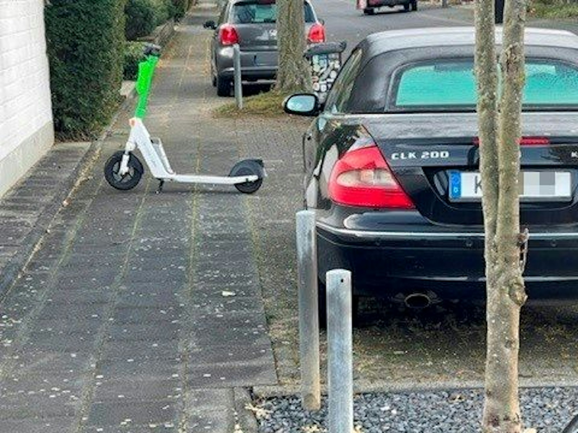 Ein E-Scooter steht quer auf einem Gehweg und blockiert den Durchgang.
