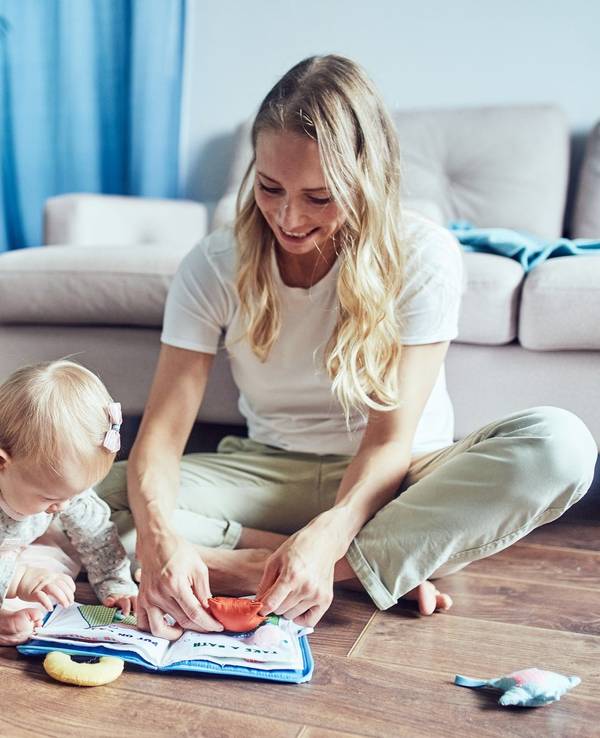 Kind und Babysitter sitzen auf dem Boden und spielen.