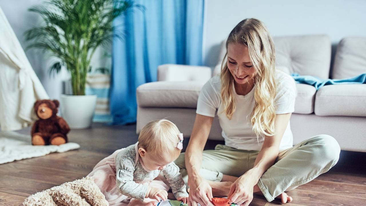 Kind und Babysitter sitzen auf dem Boden und spielen.