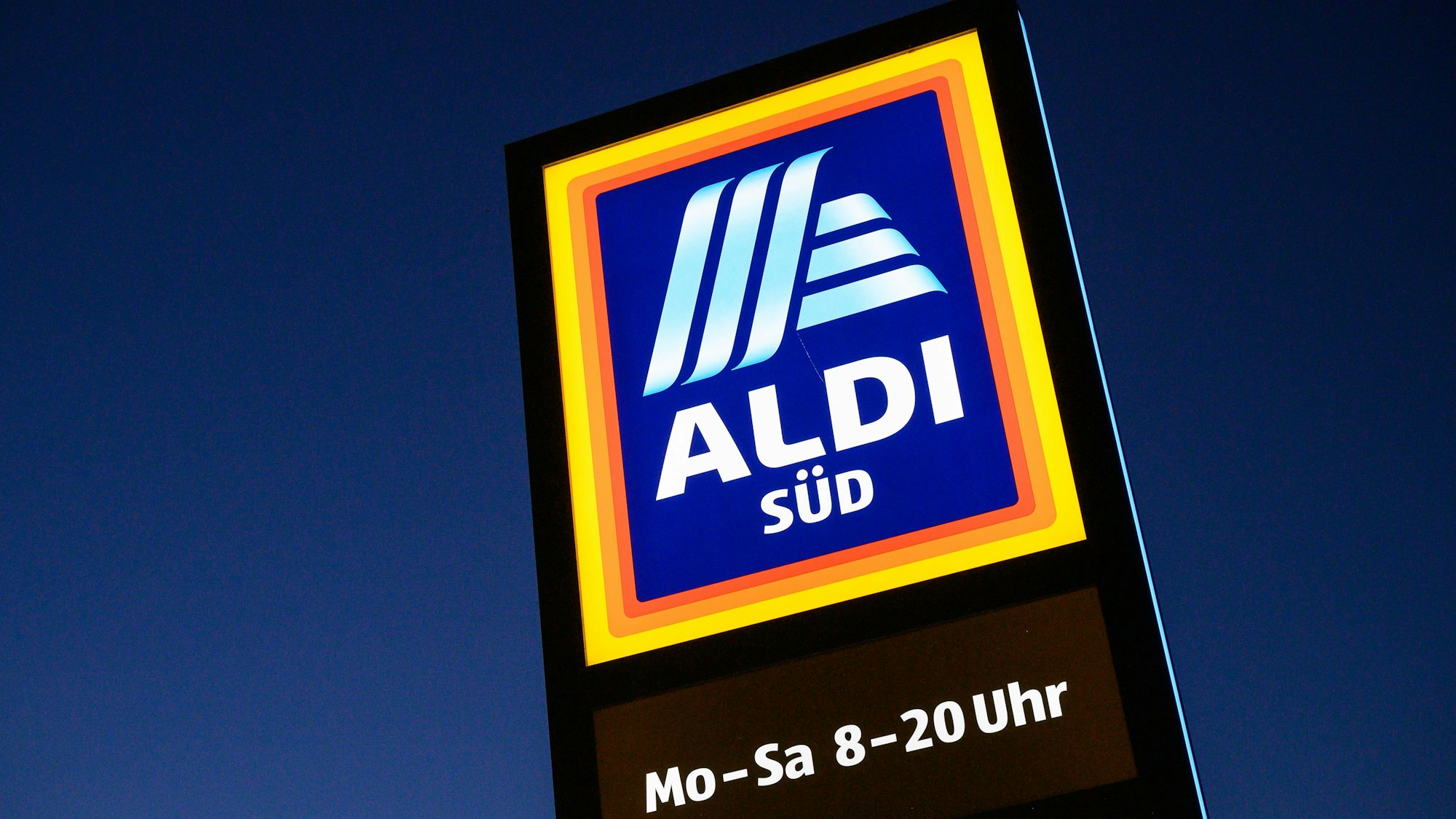 Ein Schild des Discounters Aldi Süd leuchtet.