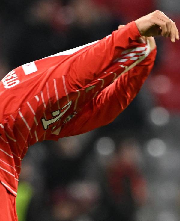 Joao Cancelo zieht sich das Trikot des FC Bayern über den Kopf.