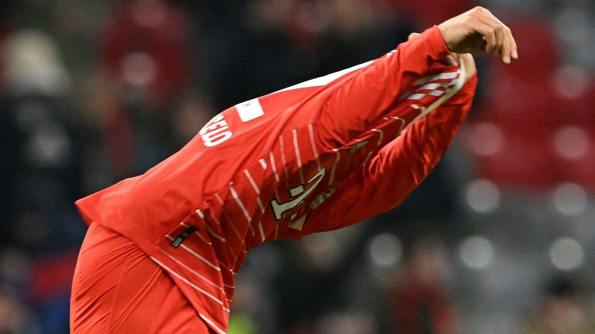 Joao Cancelo zieht sich das Trikot des FC Bayern über den Kopf.