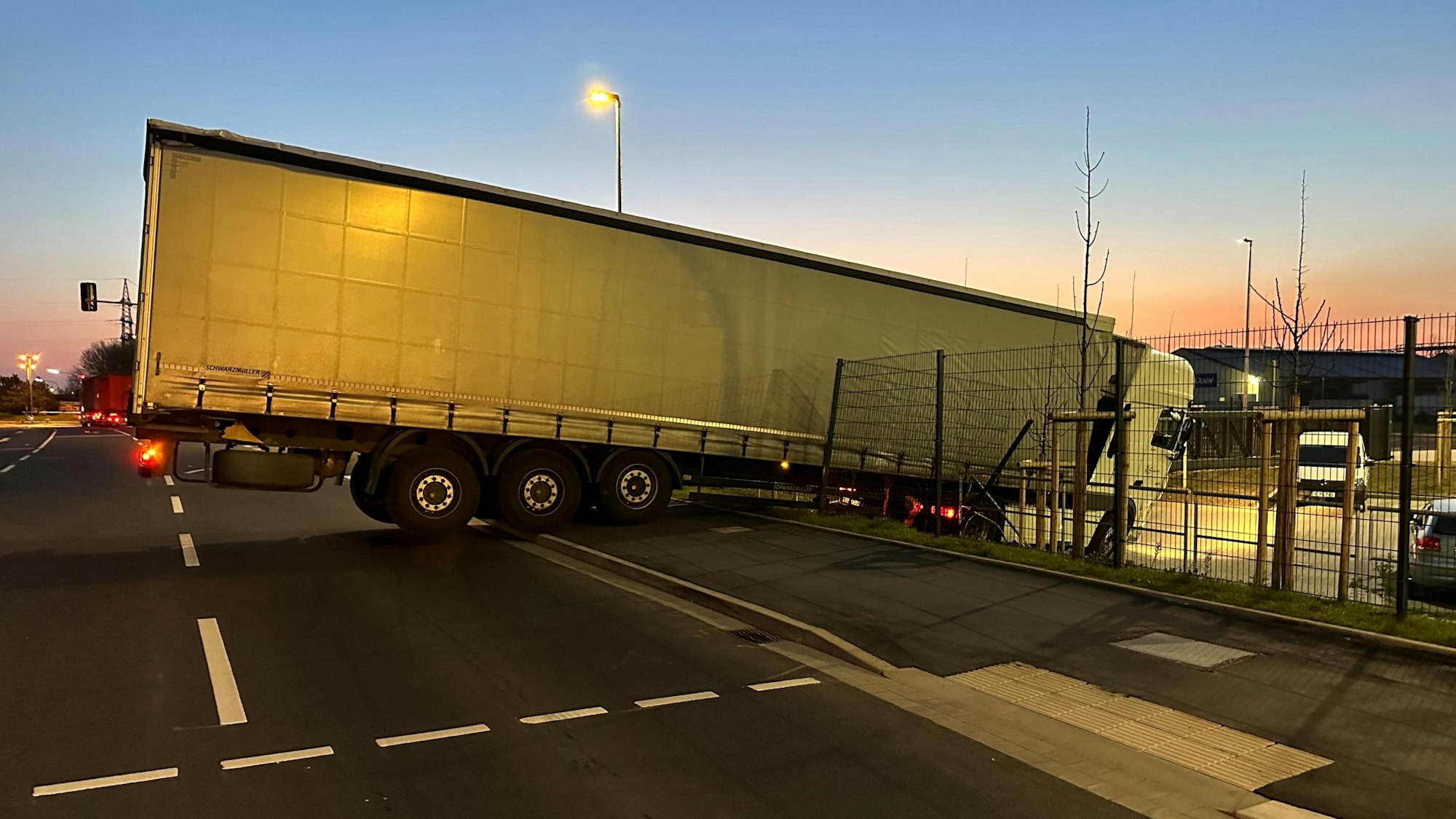 Lkw hängt an einer Unfallstelle zwischen Straße und tieferliegendem Parkplatz.