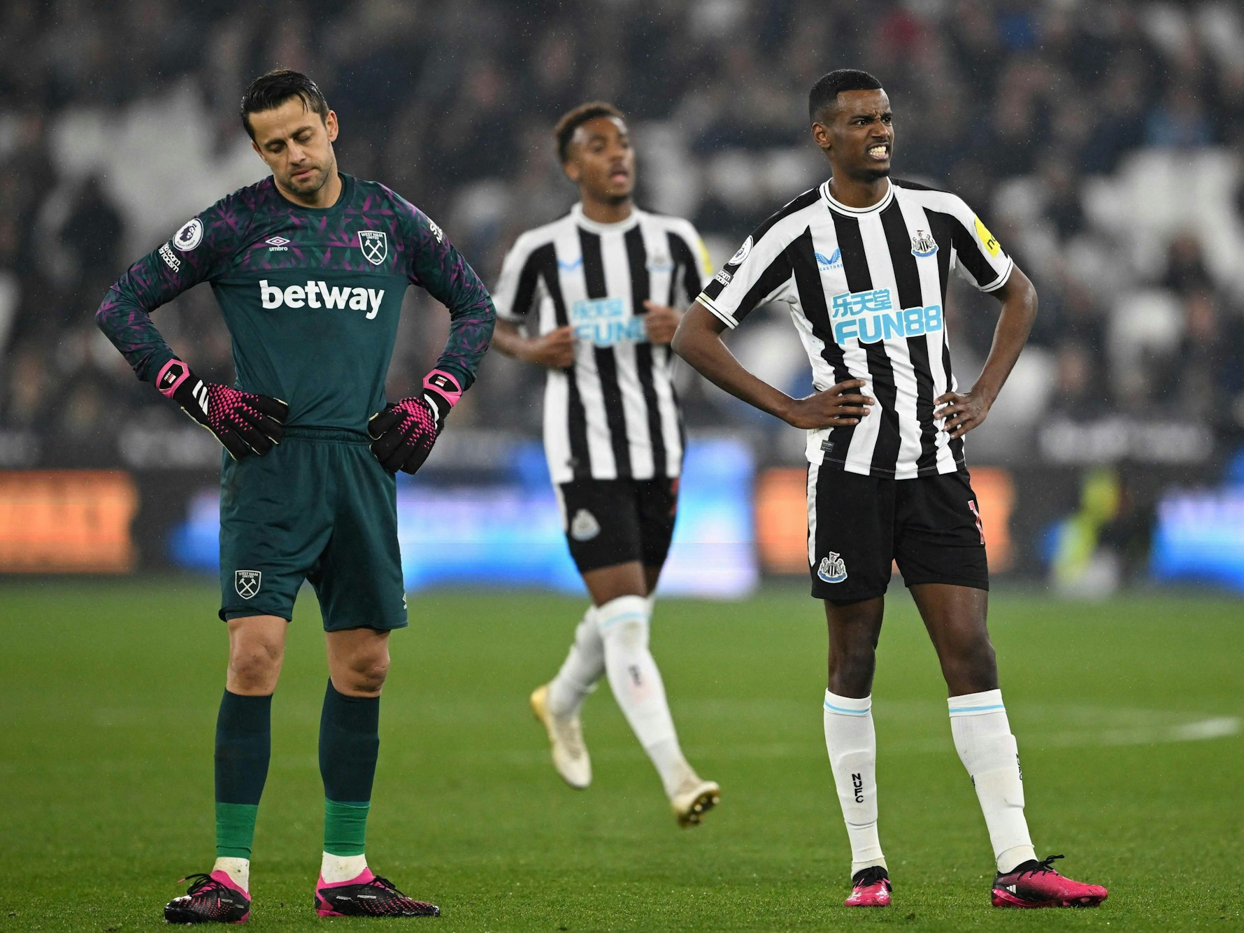 Lukasz Fabianski und Alexander Isak stehen im Spiel zwischen West Ham United und Newcastle United in ähnlicher Pose nebeneinander.